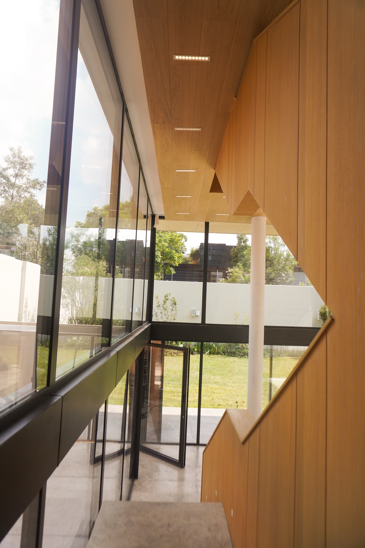 Escalera con recubrimiento de madera y cancelería de doble altura