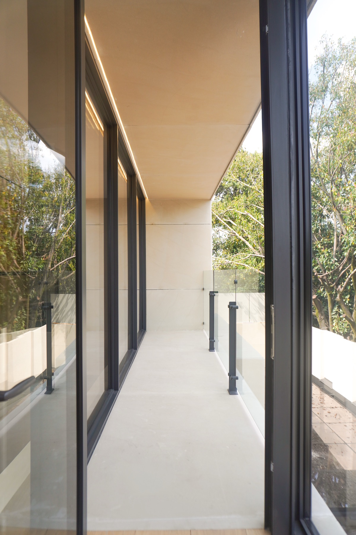 Balcón lineal con plafón de madera y barandal de cristal
