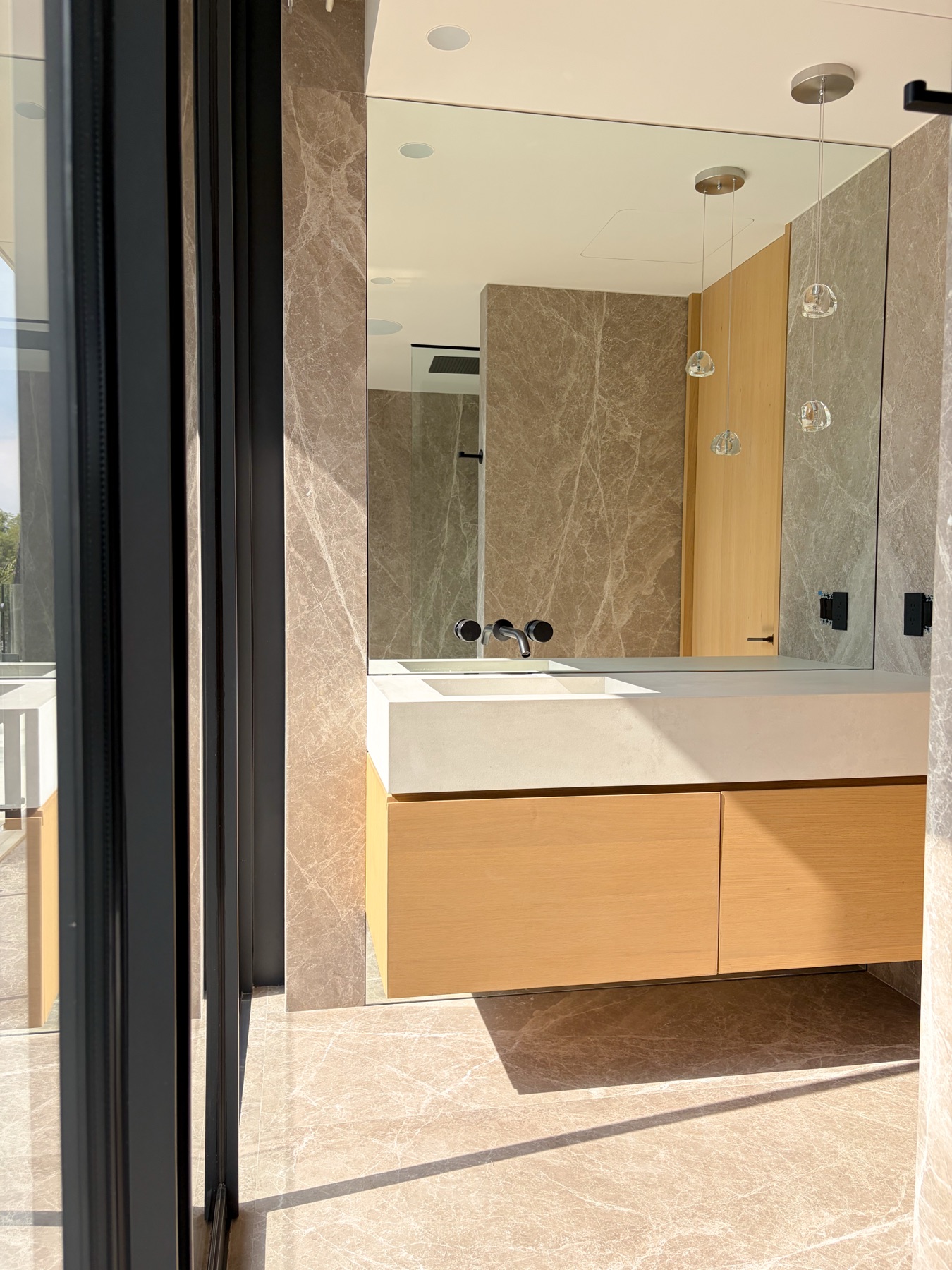 Baño con mármol, espejo de gran formato y mueble de madera